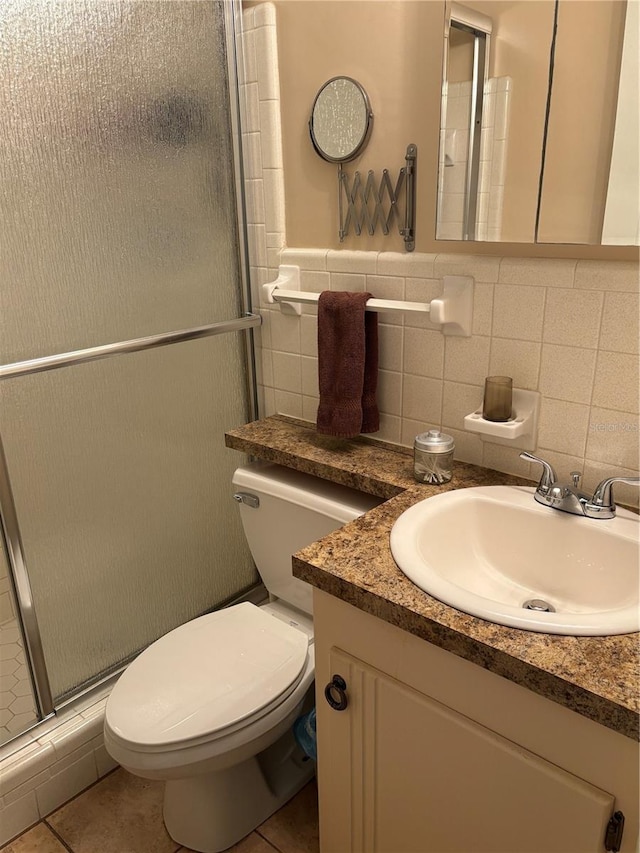 full bath with tile walls, toilet, a shower with shower door, vanity, and tile patterned floors