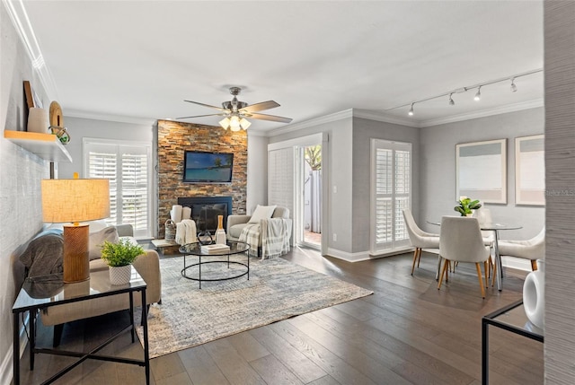 living area with baseboards, dark wood-style floors, ceiling fan, ornamental molding, and a fireplace