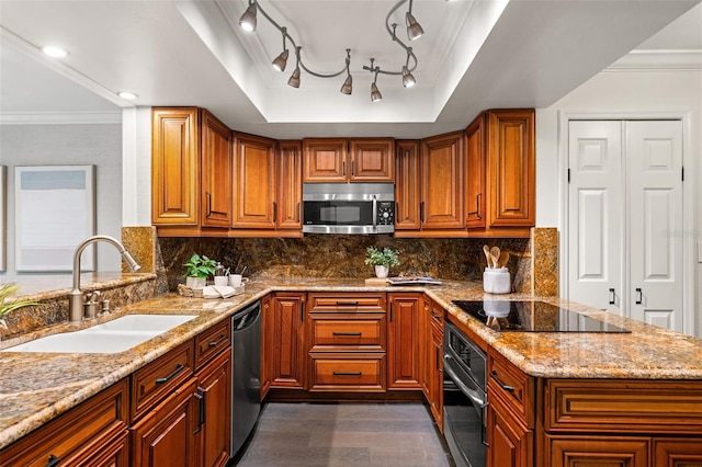 kitchen featuring light stone countertops, a sink, appliances with stainless steel finishes, brown cabinets, and a raised ceiling