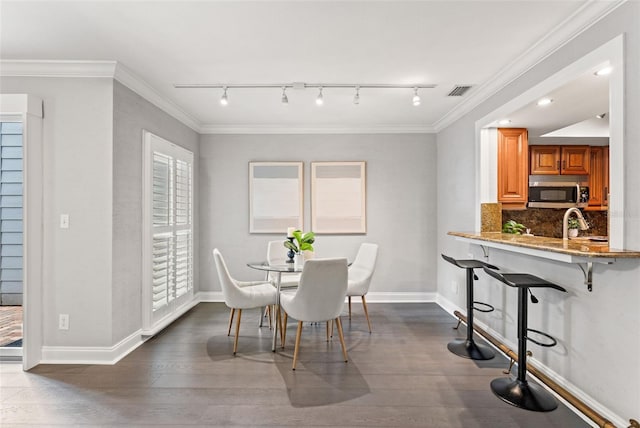 dining room with dark wood-style floors, visible vents, baseboards, and crown molding