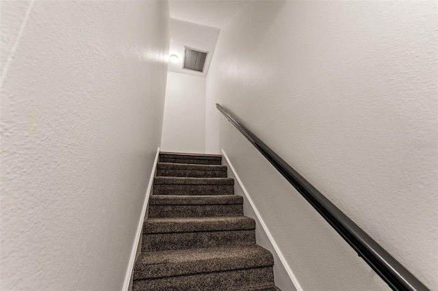 stairway with a textured wall and visible vents