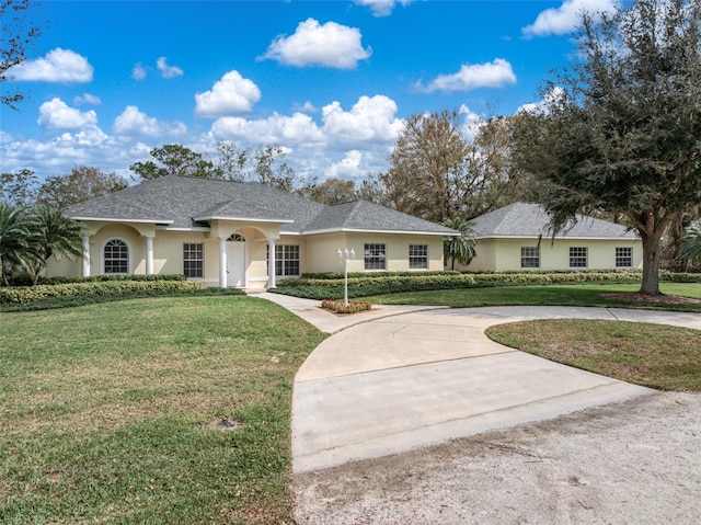 single story home featuring stucco siding, roof with shingles, concrete driveway, and a front yard