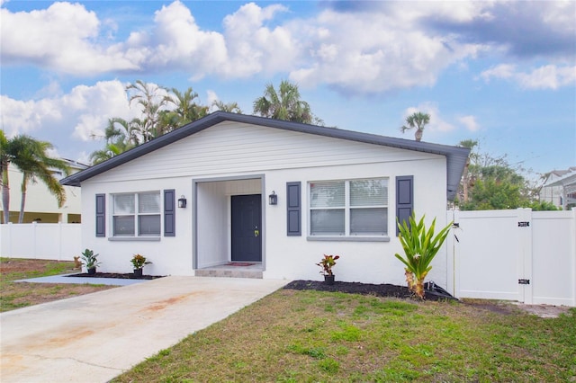 bungalow-style home featuring a gate, fence, a front lawn, and stucco siding