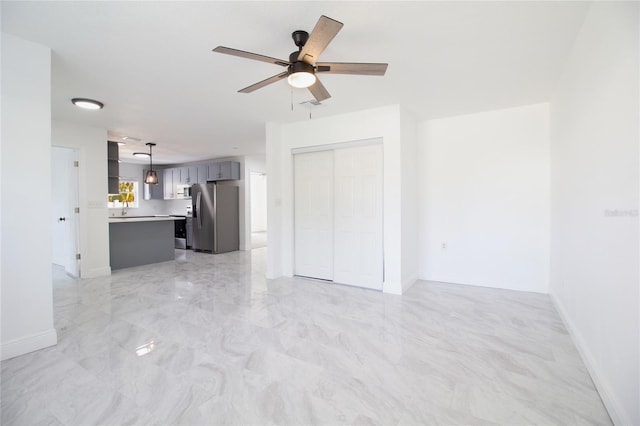 unfurnished living room with marble finish floor, a ceiling fan, and baseboards