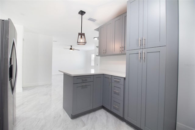 kitchen featuring light countertops, stainless steel fridge, a peninsula, and gray cabinetry