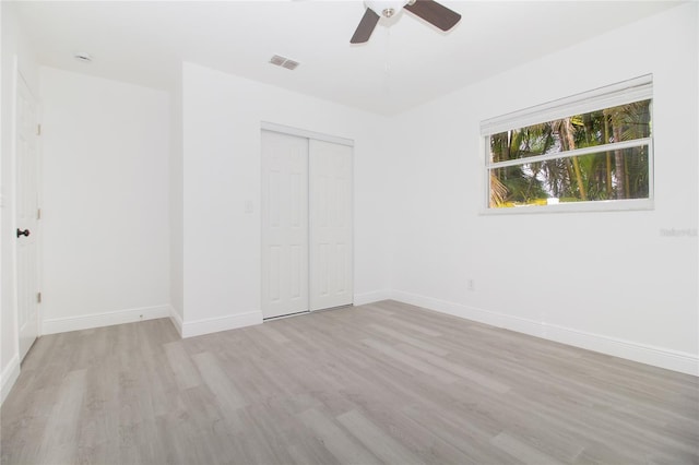 unfurnished bedroom with a ceiling fan, visible vents, baseboards, a closet, and light wood-type flooring