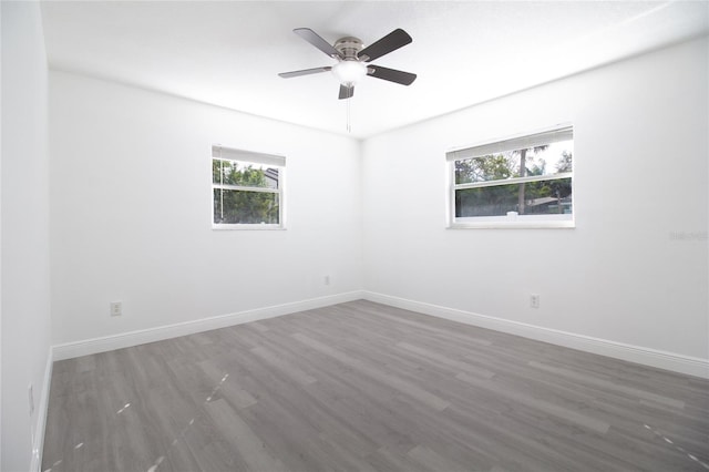 spare room featuring ceiling fan, dark wood-style flooring, and baseboards