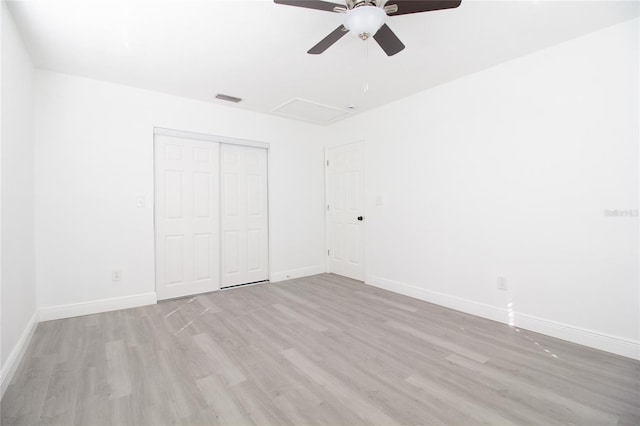 unfurnished bedroom with a closet, visible vents, light wood-style flooring, attic access, and baseboards