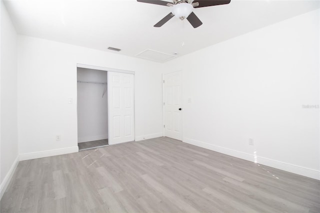 unfurnished bedroom featuring light wood finished floors, attic access, visible vents, baseboards, and a closet