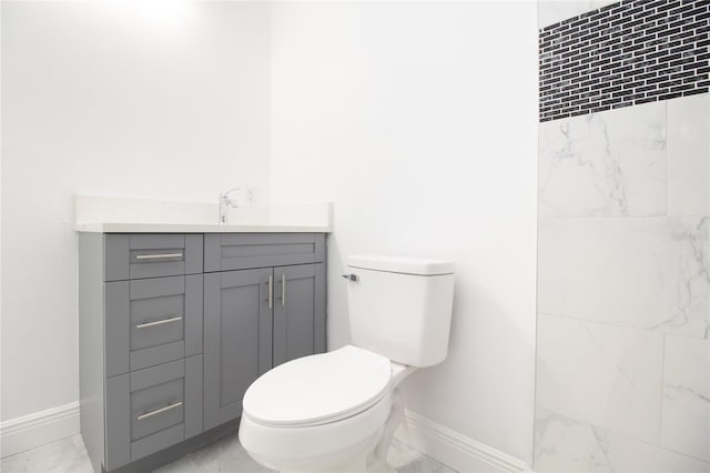 bathroom with toilet, vanity, and baseboards