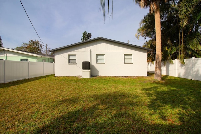 rear view of house featuring cooling unit, a fenced backyard, and a lawn