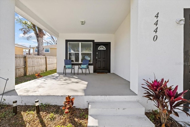 property entrance with a patio area, fence, and stucco siding