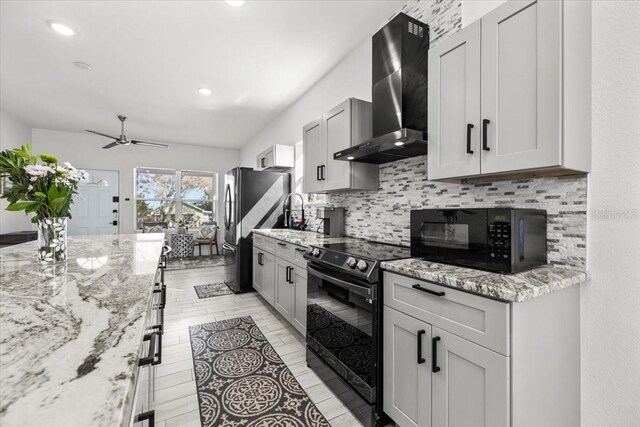 4440 58th Ave N, Saint Petersburg, FL 33714 - kitchen featuring a ceiling fan, black appliances, light stone countertops, wall chimney exhaust hood, and tasteful backsplash