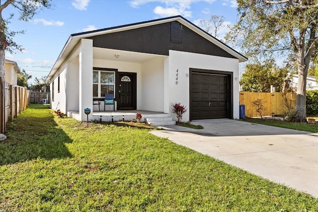 4440 58th Ave N, Saint Petersburg, FL 33714 - view of front of property featuring a garage, concrete driveway, a front lawn, and fence