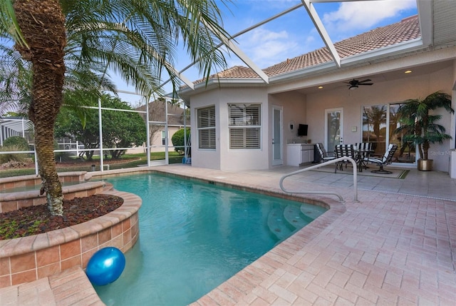 pool featuring glass enclosure, ceiling fan, and a patio area