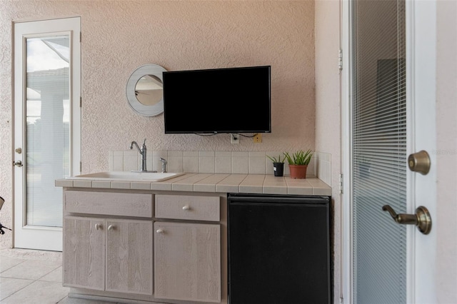 bar featuring refrigerator, a sink, and light tile patterned floors