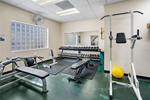 gym featuring a paneled ceiling and baseboards