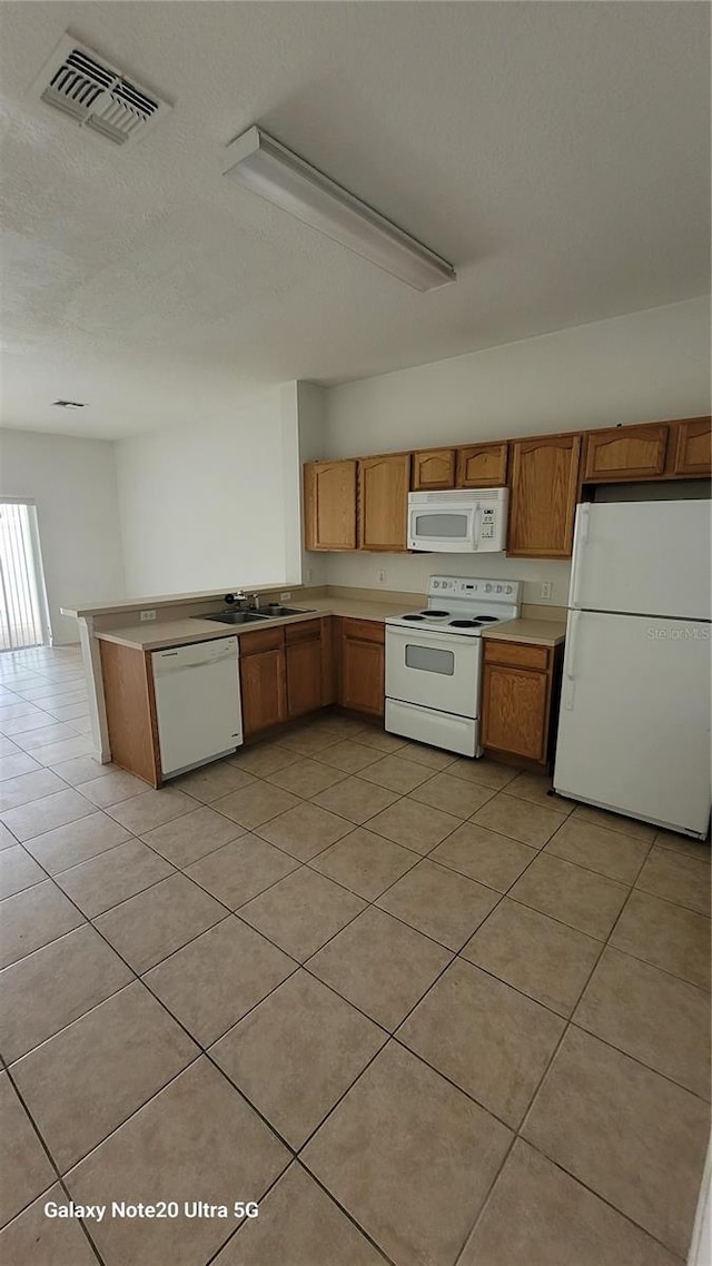 kitchen with light countertops, white appliances, brown cabinetry, and visible vents