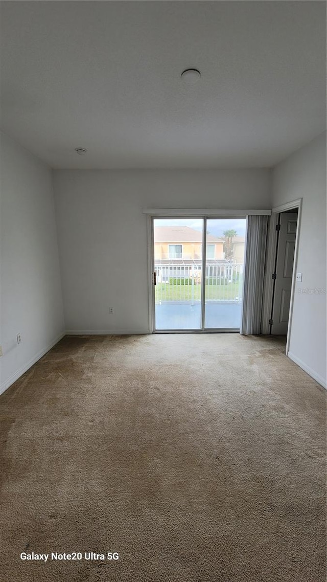 carpeted empty room featuring baseboards