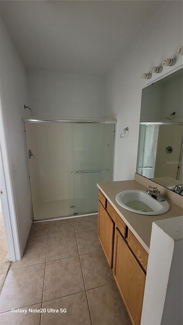 bathroom featuring tile patterned flooring, vanity, and a shower stall