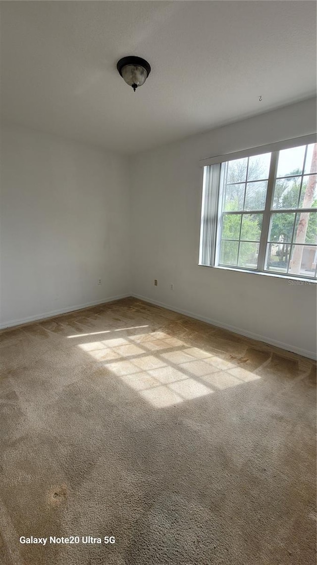 unfurnished room featuring light carpet and baseboards