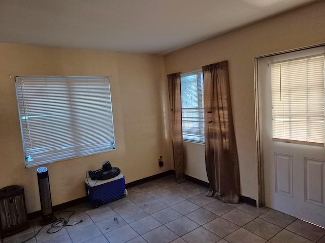 interior space with baseboards, light tile patterned flooring, and a healthy amount of sunlight