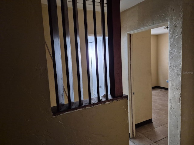 hallway with a textured wall and tile patterned floors