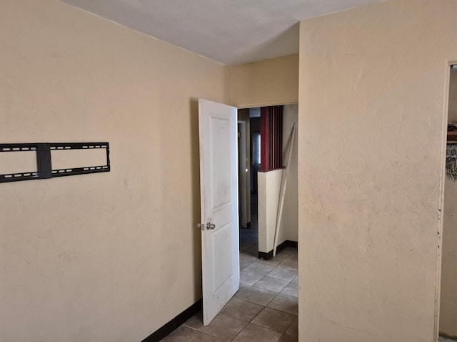 hallway featuring tile patterned flooring and baseboards