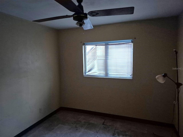 empty room featuring ceiling fan and baseboards