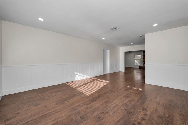 unfurnished room featuring recessed lighting, wood finished floors, visible vents, and wainscoting