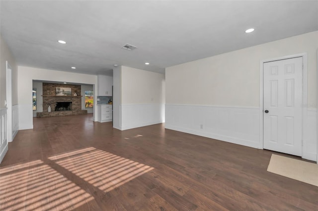 unfurnished living room featuring visible vents, wood finished floors, recessed lighting, a fireplace, and wainscoting