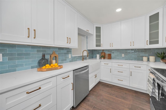 kitchen featuring dishwasher, light countertops, decorative backsplash, and a sink