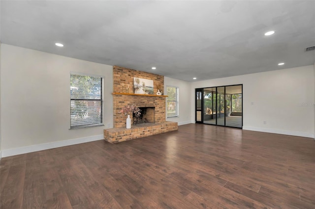 unfurnished living room featuring wood finished floors, a healthy amount of sunlight, and baseboards