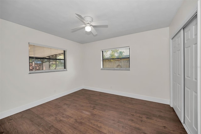 unfurnished bedroom featuring ceiling fan, a closet, baseboards, and dark wood-style floors