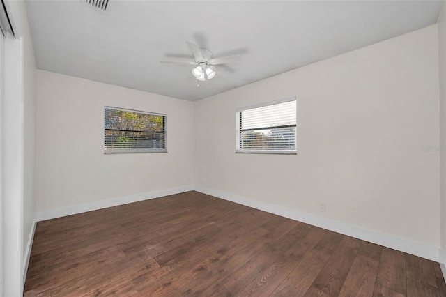 unfurnished room with visible vents, baseboards, dark wood-style flooring, and a ceiling fan