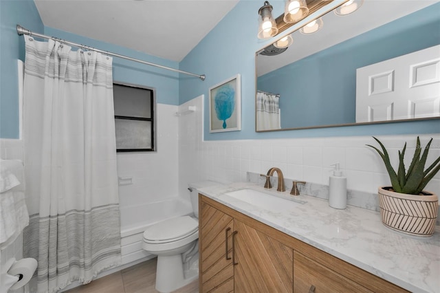 bathroom featuring a wainscoted wall, shower / bath combo with shower curtain, toilet, vanity, and tile walls