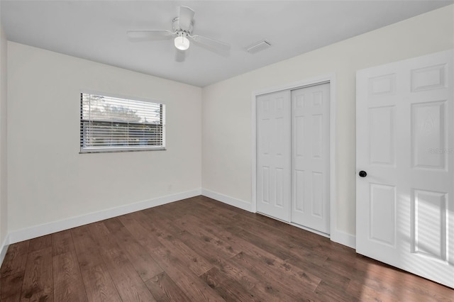 unfurnished bedroom with a ceiling fan, baseboards, visible vents, dark wood finished floors, and a closet