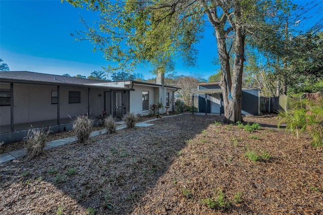 exterior space with an outbuilding, stucco siding, and fence