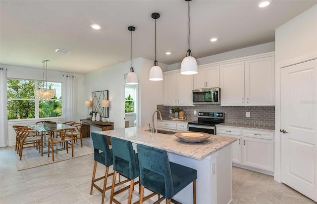 kitchen with a sink, stainless steel appliances, backsplash, and white cabinetry