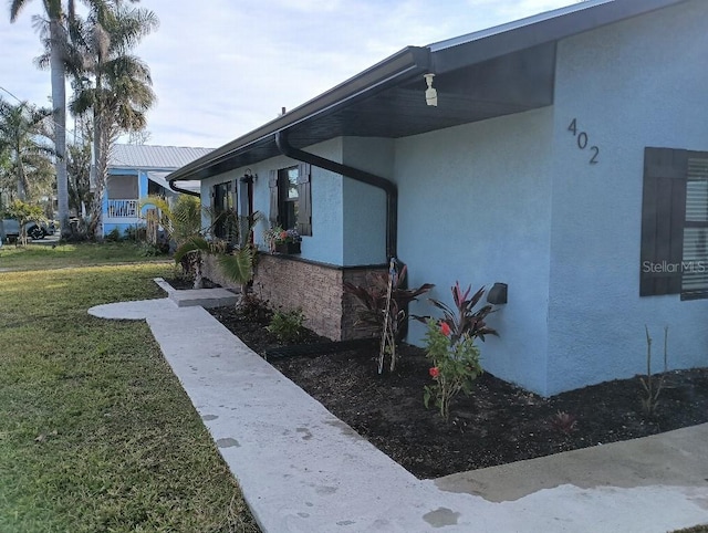 view of property exterior featuring stone siding, a lawn, and stucco siding