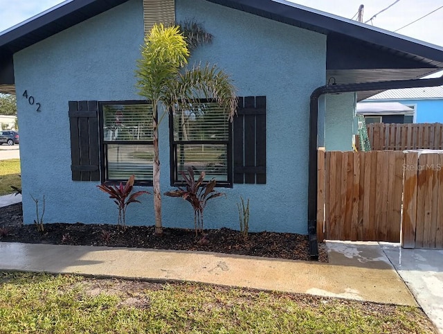 view of side of property featuring fence and stucco siding