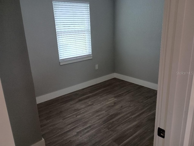 unfurnished room with baseboards and dark wood finished floors