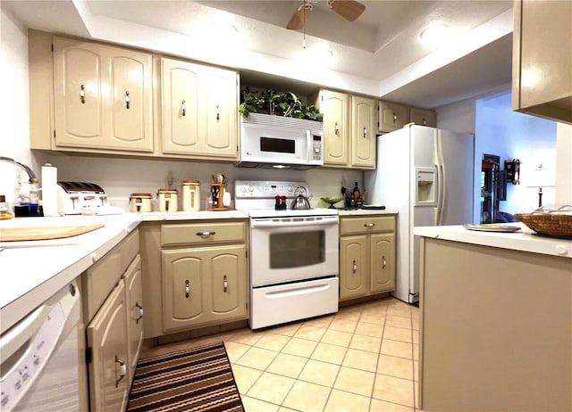 kitchen featuring light tile patterned floors, ceiling fan, white appliances, light countertops, and a tray ceiling