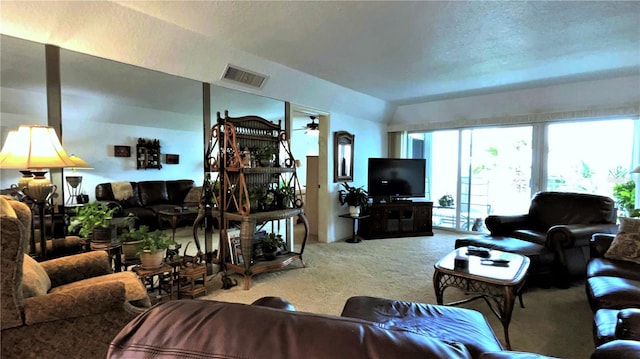 living area with carpet, lofted ceiling, visible vents, a ceiling fan, and a textured ceiling