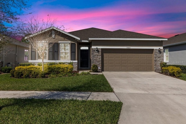 view of front of home featuring an attached garage, a shingled roof, driveway, stone siding, and a front yard