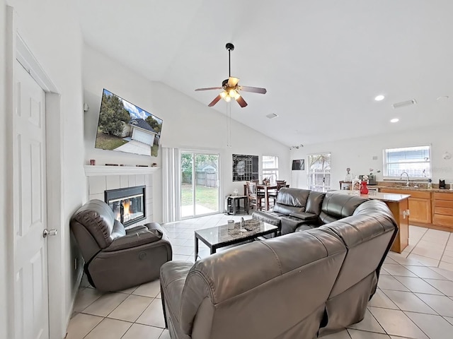 living area with light tile patterned floors, ceiling fan, a fireplace, and high vaulted ceiling