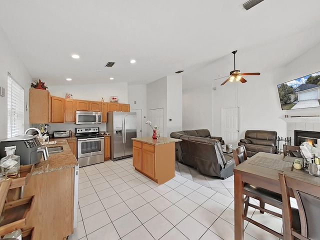 kitchen featuring light stone counters, light tile patterned flooring, stainless steel appliances, a kitchen island, and open floor plan