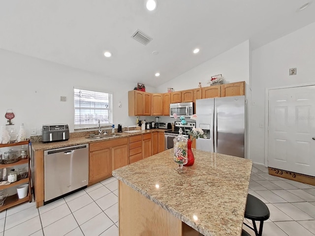 kitchen featuring light tile patterned floors, appliances with stainless steel finishes, a sink, and light stone counters