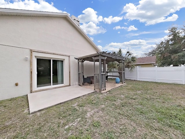 rear view of house with stucco siding, a lawn, fence, and a pergola