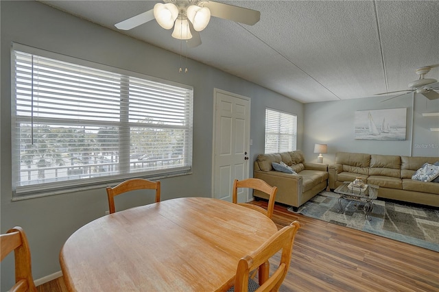 dining space featuring a ceiling fan, a textured ceiling, and wood finished floors